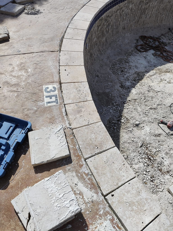 Detailed view of coping tile installation in progress around an empty pool by J.R. Pools in Lubbock, TX.