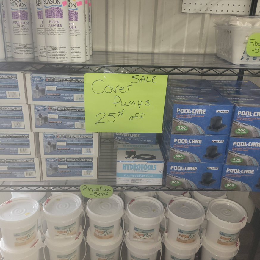 Shelves displaying pool cover pumps and Phosfloc chemicals at Pool Queen in Fairmont, WV.