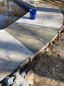 Fresh concrete being applied for repair or leveling around a pool deck by HNO Waterproofing & Slab Lifting Pros in Concord, NC.