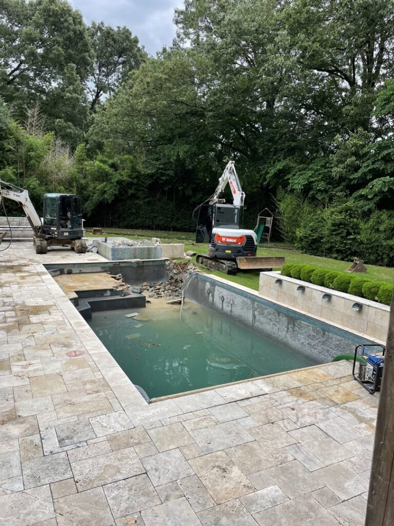 A swimming pool undergoing demolition and filling with two excavators on site by East Shelby Demolition & Pool Removal in Olive Branch, MS.