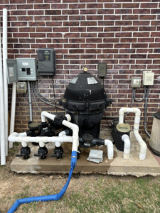 Pool equipment maintenance by AW Pool Service in Tulsa, OK, showing a large filter and connected blue hose.