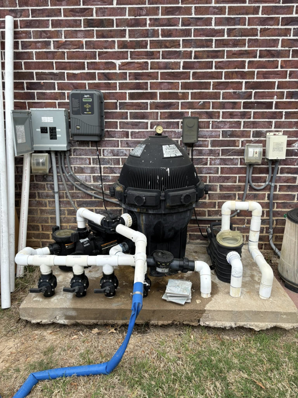 Pool equipment maintenance by AW Pool Service in Tulsa, OK, showing a large filter and connected blue hose.