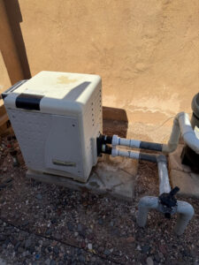 A pool heater installation with connecting pipes, showcasing services by Purpose Pools in Henderson, NV.