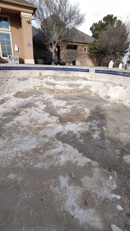 The interior surface of an empty pool showing steps and rough texture, ready for repair by J.R. Pools in Lubbock, TX.