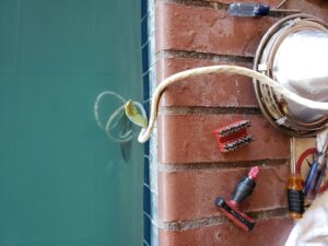 A pool light fixture being repaired with tools next to a clean pool by Thompson Pools in Statesboro, GA.
