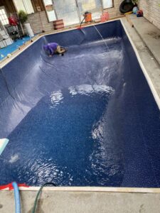 A Battle Born Pool & Spa technician installing a new liner in an indoor swimming pool in Sparks, NV.