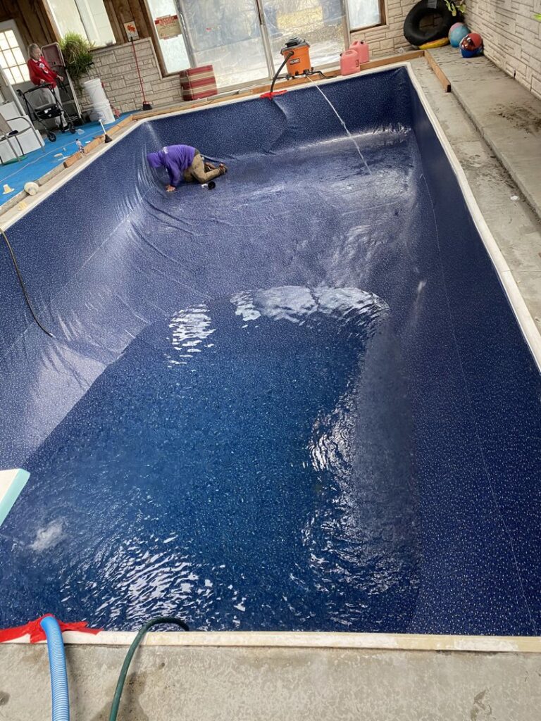 A Battle Born Pool & Spa technician installing a new liner in an indoor swimming pool in Sparks, NV.