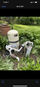A pool pump and filter system surrounded by greenery, maintained by Chlorine Clean Pool Services in Wilmington, DE.