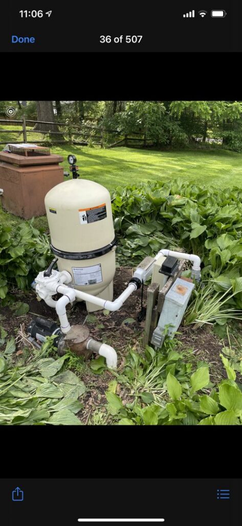 A pool pump and filter system surrounded by greenery, maintained by Chlorine Clean Pool Services in Wilmington, DE.
