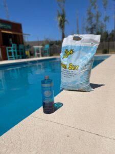 Pool salt and super clarifier products on the edge of a clean pool, used by Pool Services of Wilmington in Wilmington, NC.