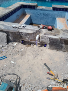 A pool and spa undergoing renovation with exposed plumbing and construction tools by J.R. Pools in Lubbock, TX.