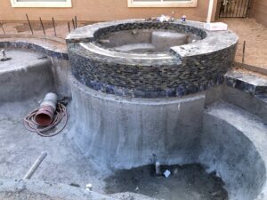 A swimming pool and spa under construction, with mosaic tiling being applied to the spa by Greencare.net POOL Builder in Las Vegas, NV