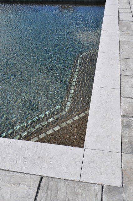 A close-up detail of pool steps with blue tiling and clean coping by Christman Pool Service in Portland, ME.