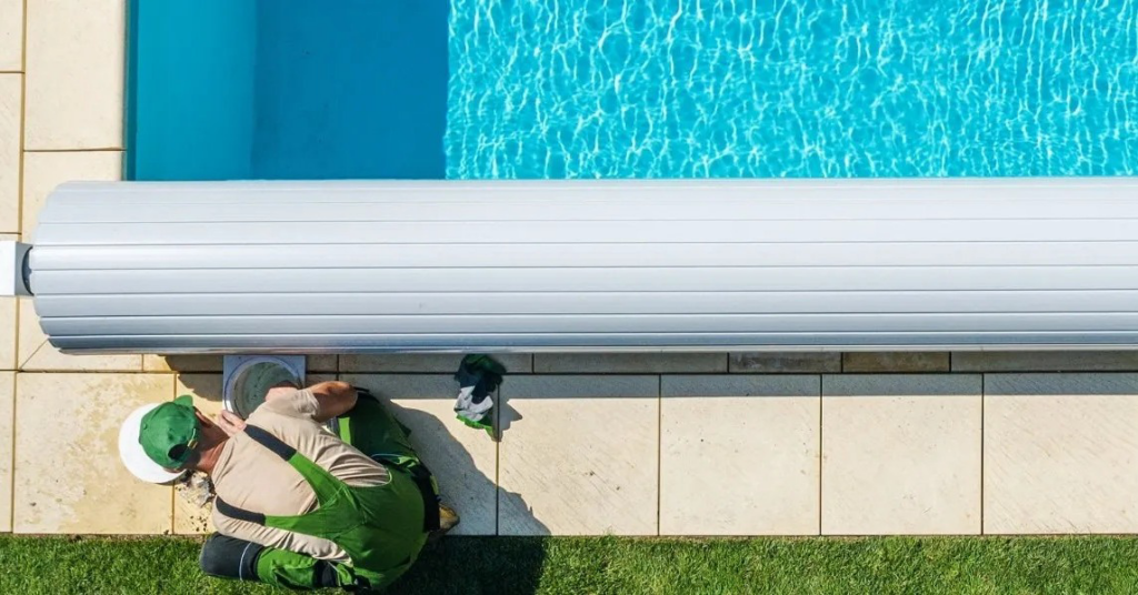 A pool technician performing maintenance or service on pool equipment next to a swimming pool with a cover by Sun Leisure Pools & Spas in Sparks, NV.