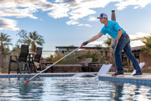 A pool technician from Echo Pool Service skimming a residential pool in Mesquite, NV, ensuring crystal clear water.