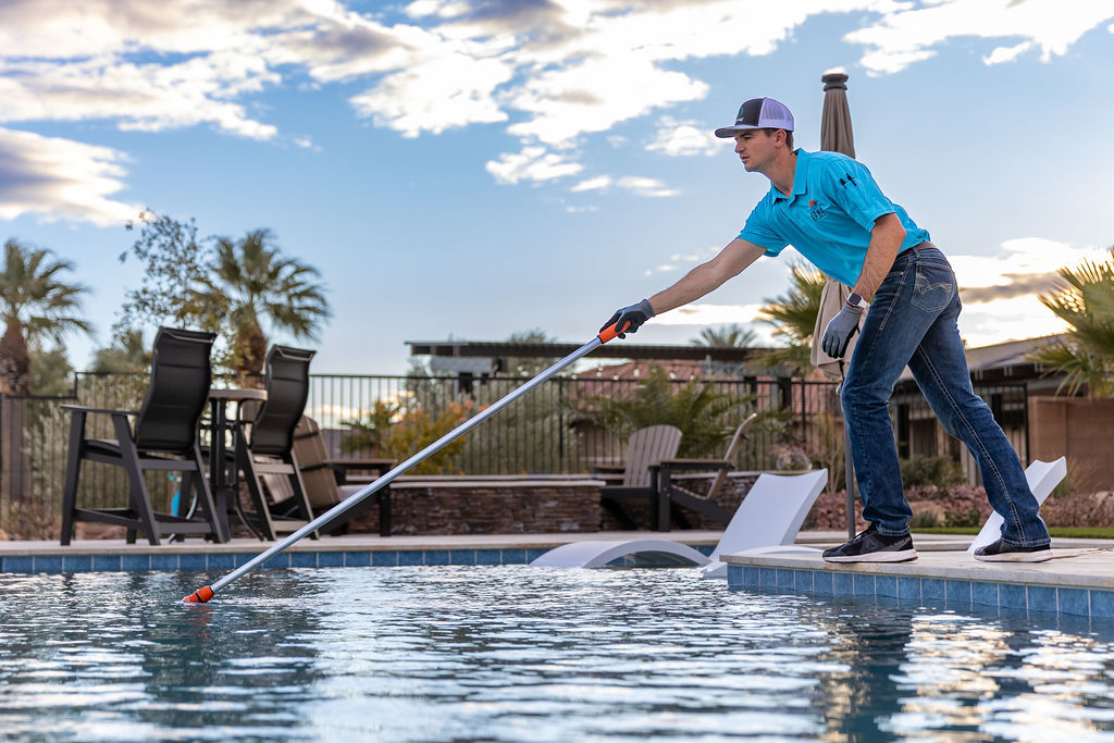 A pool technician from Echo Pool Service skimming a residential pool in Mesquite, NV, ensuring crystal clear water.