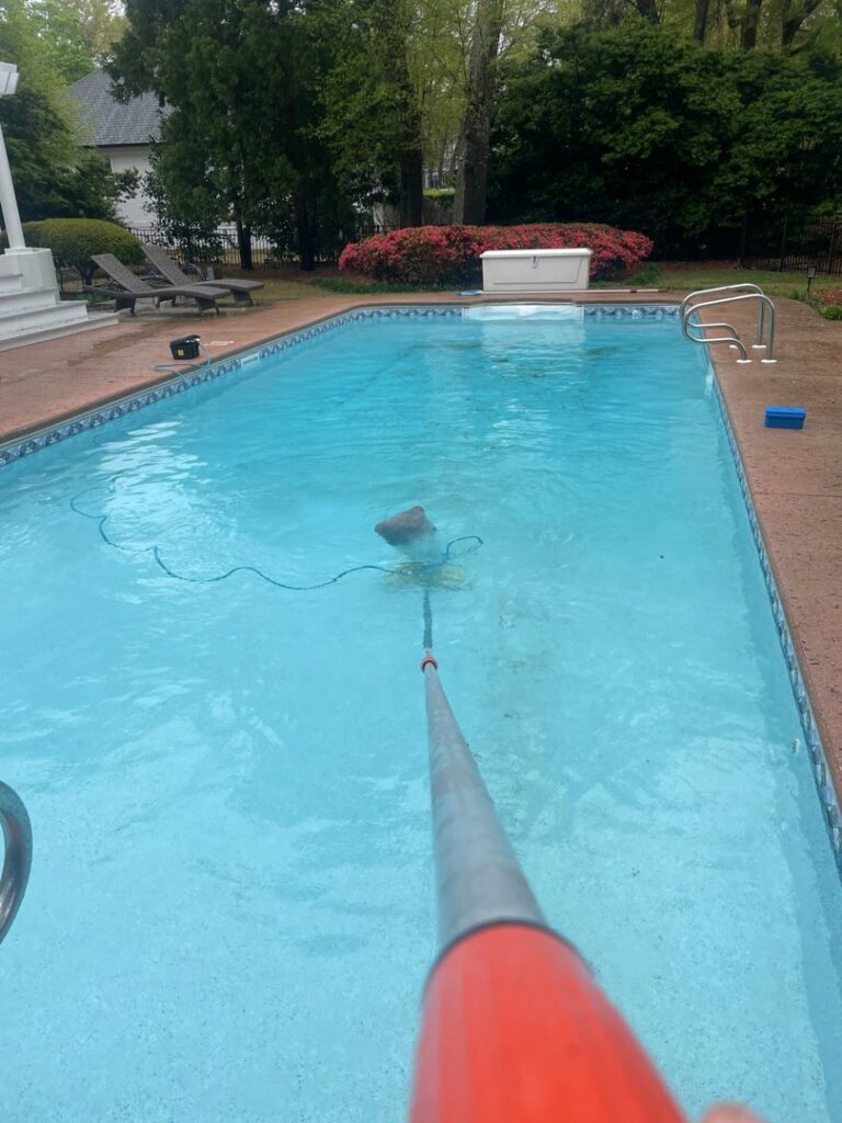 A pool technician vacuuming a residential swimming pool for Pool Services of Wilmington in Wilmington, NC.