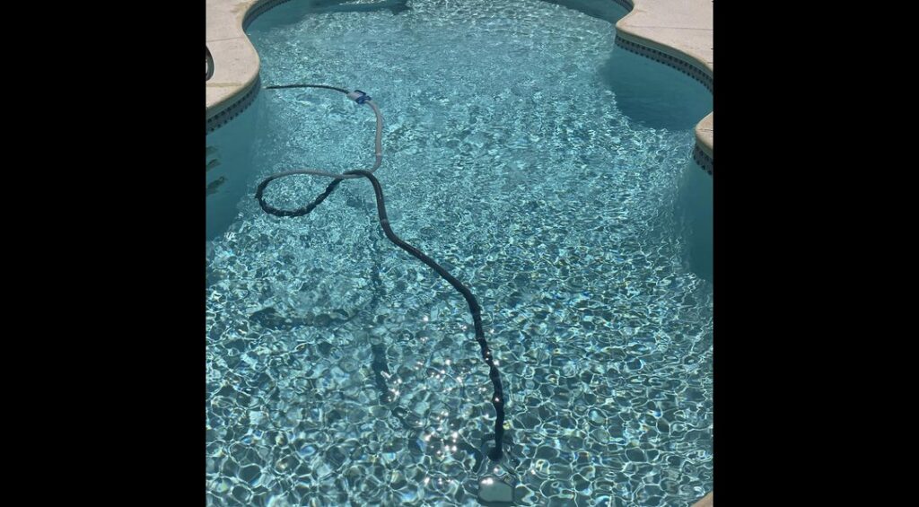 A robotic pool vacuum cleaning the bottom of a sparkling clean pool by Overflow Poolz LLC in Las Vegas, NV.