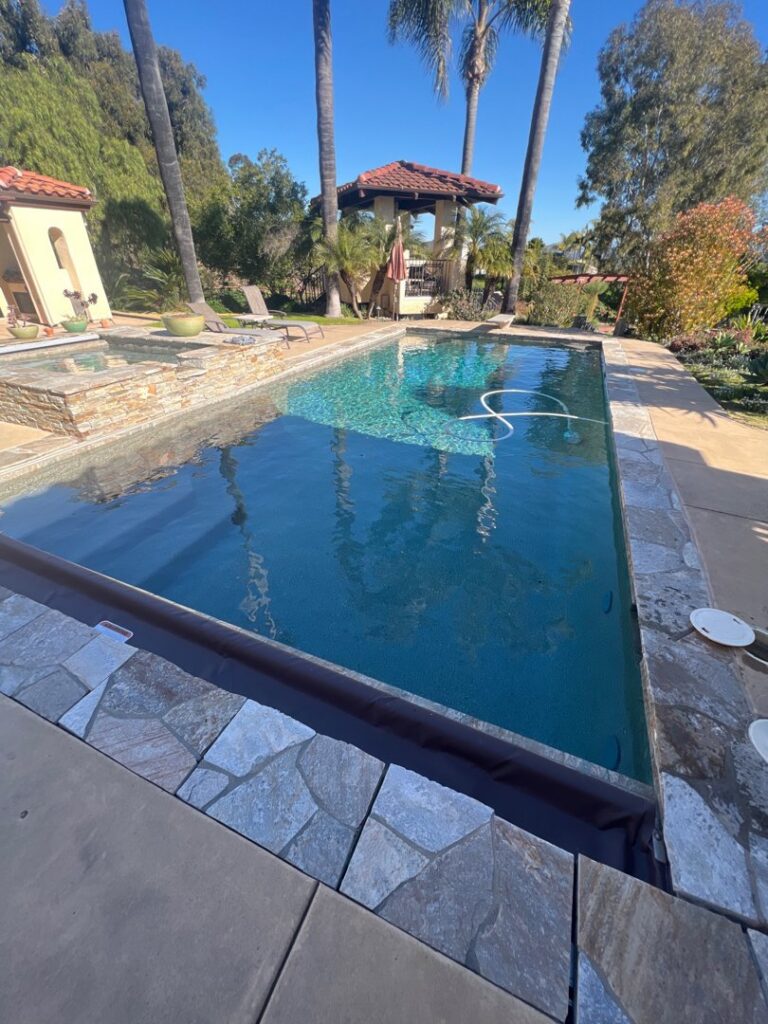 A pool vacuum hose visible in a clean swimming pool, demonstrating cleaning services by Priority Pools LV in Las Vegas, NV