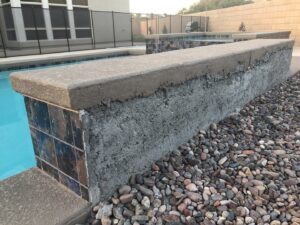 A detailed view of a pool wall with decorative tiling and coping by Greencare.net POOL Builder in Las Vegas, NV