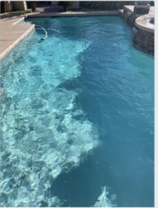 A pool undergoing water clarity treatment, showing cloudy and clear sections, serviced by Overflow Poolz LLC in Las Vegas, NV.