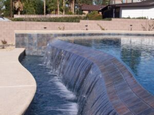 A custom pool featuring an elegant curved waterfall, expertly installed by Steve Breck Pools in Las Vegas, NV.