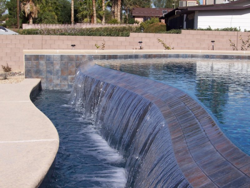 A custom pool featuring an elegant curved waterfall, expertly installed by Steve Breck Pools in Las Vegas, NV.