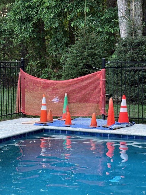 A pool work area secured with safety cones and netting, indicating ongoing leak repair or maintenance by South Shore Leak Solutions in Quincy, MA