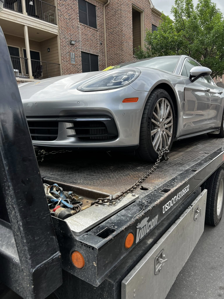 A silver Porsche Panamera secured on a flatbed tow truck, ready for transport by Heavy Hookz Towing in Fort Worth, TX.
