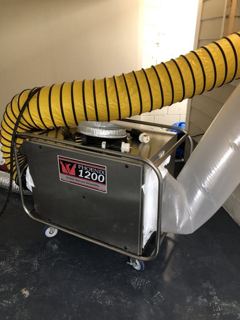 Portable desiccant dehumidifier with yellow ducting used for water damage drying by Express Restoration in Edmond, OK.