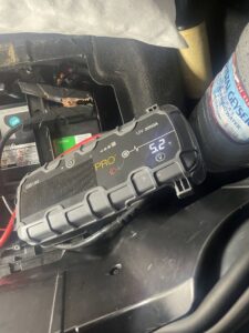 A portable jump starter connected to a car battery in the engine bay, providing a jump start service by Emergency Towing Sacramento, CA.