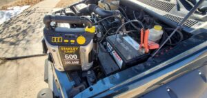 A portable jump starter connected to a car battery for a jump start service by Liberty Auto Rescue in Colorado Springs, CO.