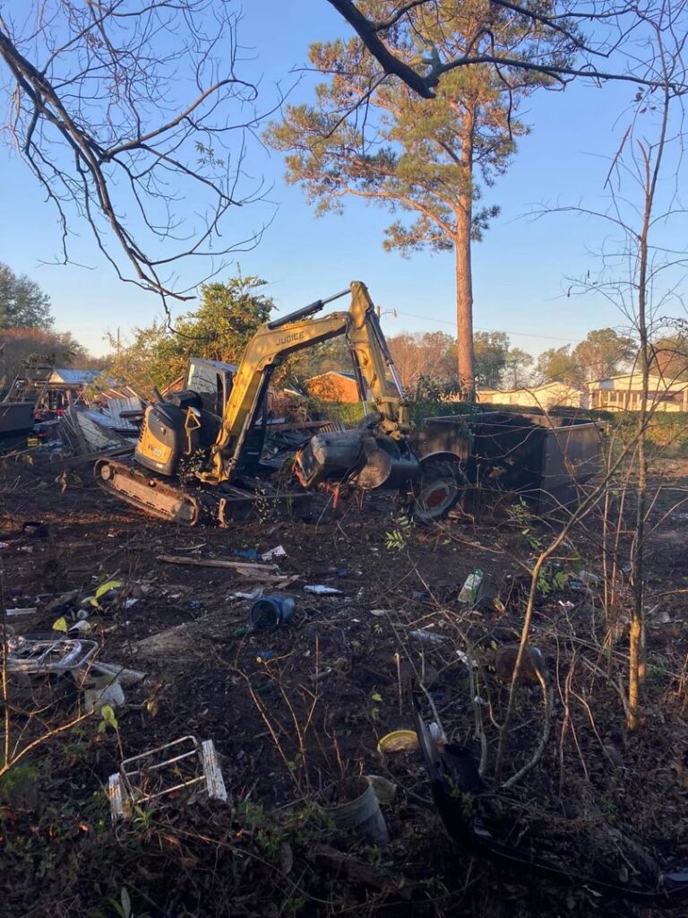 An excavator from Judice Dirt & Demolition performing post-fire cleanup and demolition in a burnt-out area in Lafayette, LA.