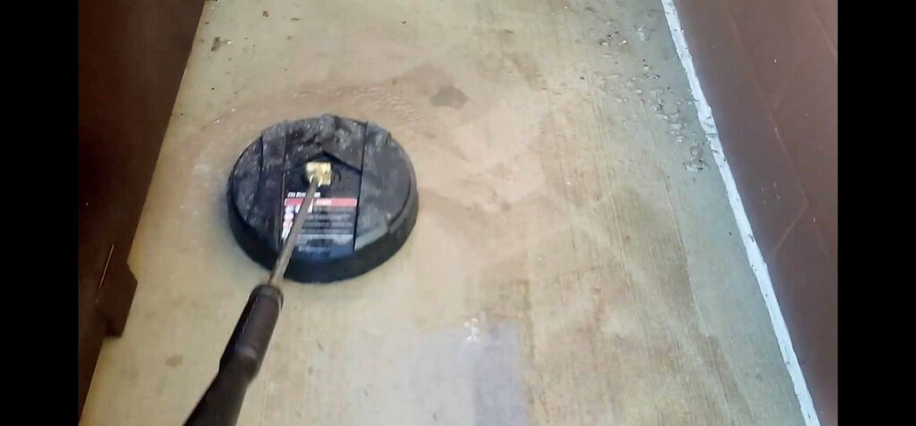 A pressure washer attachment cleaning a concrete surface, demonstrating exterior cleaning services by Way Too Bright Services LLC in Rockford, IL.