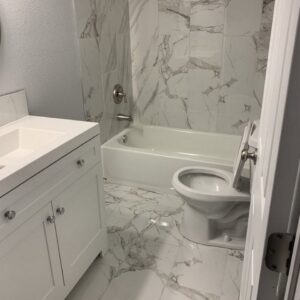 A pristine bathroom featuring a white vanity, toilet, and elegant marble-look tiles, cleaned by 307 Maid in Cheyenne, WY.