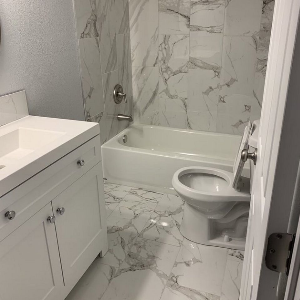 A pristine bathroom featuring a white vanity, toilet, and elegant marble-look tiles, cleaned by 307 Maid in Cheyenne, WY.