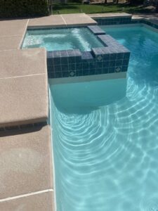A pristine blue-tiled pool and attached spa, demonstrating the quality work of Pool Tile Cleaning Vegas in Las Vegas, NV.