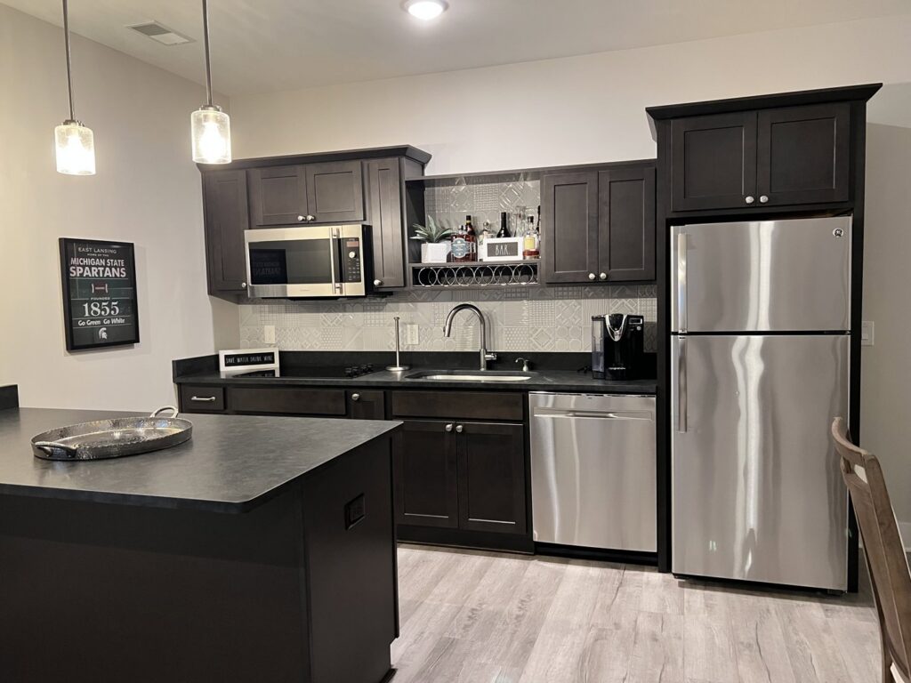 A pristine kitchen featuring dark cabinets, stainless steel appliances, and an island, cleaned by A To Zen in Lansing, MI.