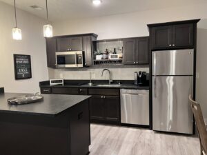 A pristine kitchen featuring dark cabinets, stainless steel appliances, and an island, cleaned by A To Zen in Lansing, MI.