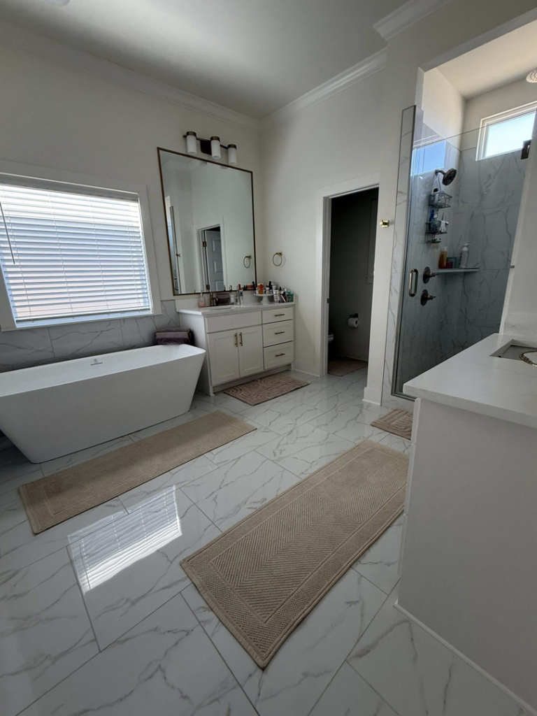 A pristine, modern bathroom with a freestanding tub, shower, and clean tiled floor, showcasing cleaning by Global Provisions, AR in Fayetteville, AR.
