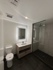 A pristine modern bathroom featuring a vanity, illuminated mirror, and glass shower, cleaned by Cleaners of Arizona in Chandler, AZ.