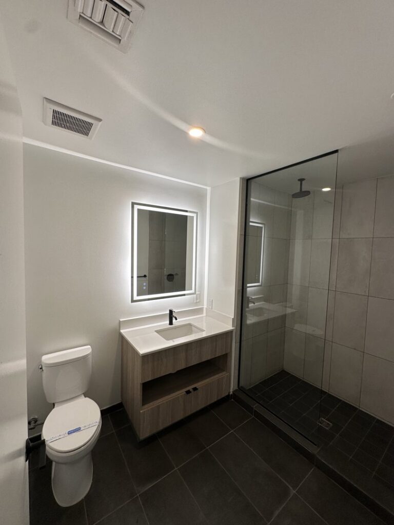 A pristine modern bathroom featuring a vanity, illuminated mirror, and glass shower, cleaned by Cleaners of Arizona in Chandler, AZ.