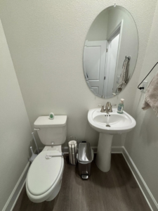 A pristine powder room with a toilet and pedestal sink, expertly cleaned by Saari's Cleaning Services LLC in Jacksonville, FL.