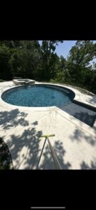 A pristine round swimming pool with a spa and a cleaning pole on the deck, serviced by AW Pool Service in Tulsa, OK.