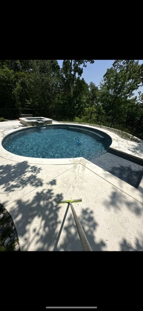 A pristine round swimming pool with a spa and a cleaning pole on the deck, serviced by AW Pool Service in Tulsa, OK.