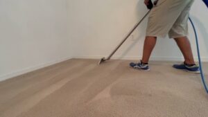 A professional house cleaner performing carpet cleaning with a wand in a residential home by Cleaning Partners in Tampa, FL