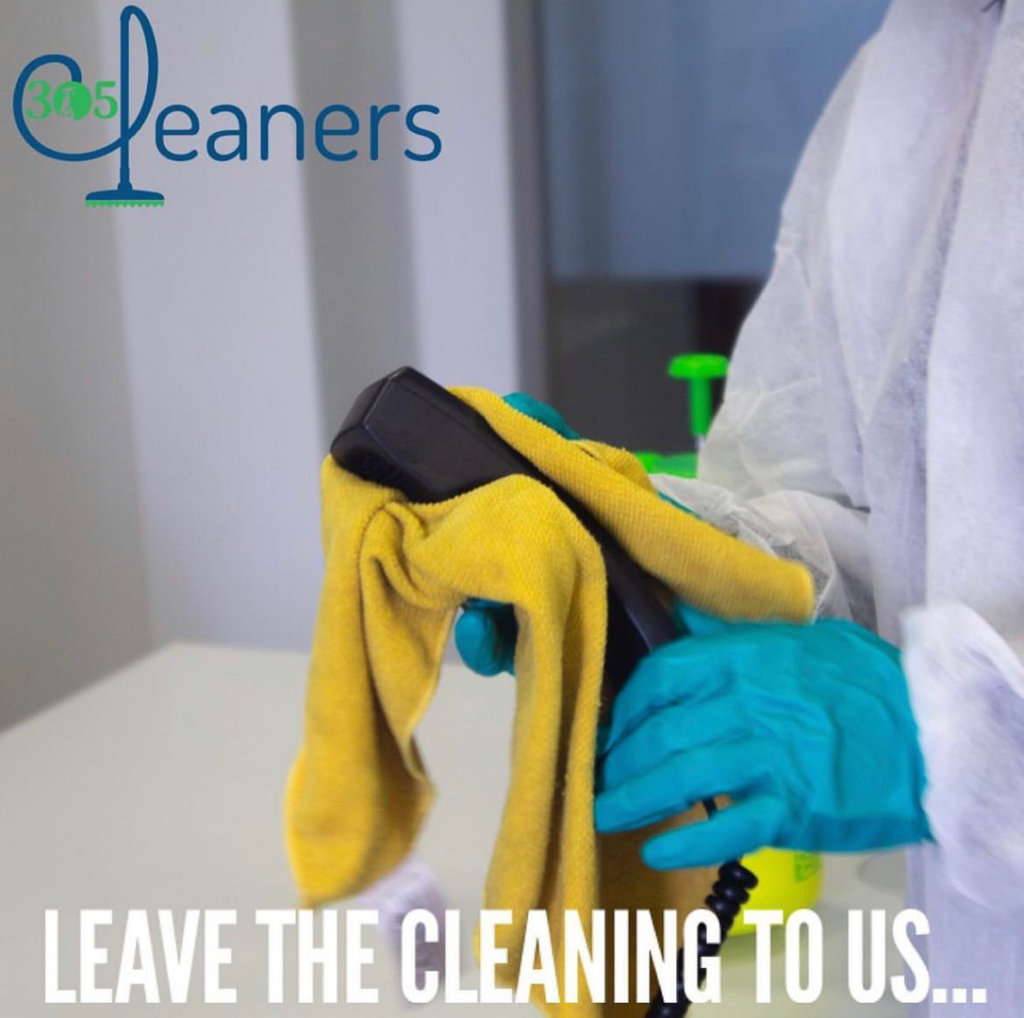A professional cleaner in protective gear wiping a surface with a yellow cloth for 305 Cleaners Corp in Miami, FL.