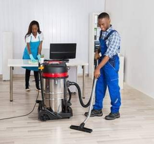 Professional cleaners vacuuming a floor and wiping a desk at Moore & Moore Cleaning Service LLC in Jackson, MS.