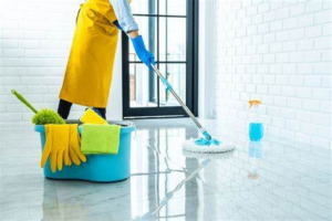 A professional cleaner mopping a tiled floor with cleaning supplies nearby for PAP-Cleaning Services in Fort Lauderdale, FL.