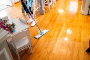A professional house cleaner mopping a shiny wooden floor for Unity Cleaning in Chicago, IL.